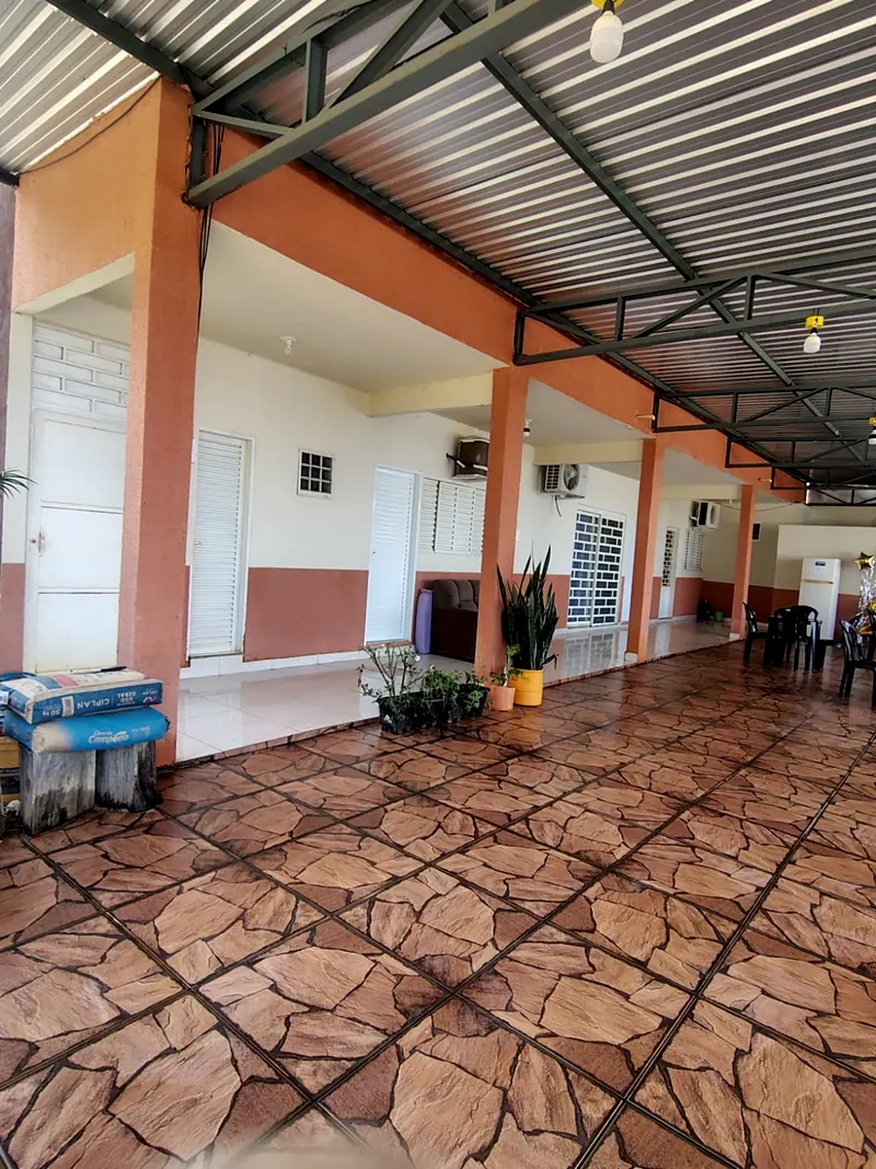 Corredor coberto com as portas dos quartos da casa de baixo, de piso de pedra