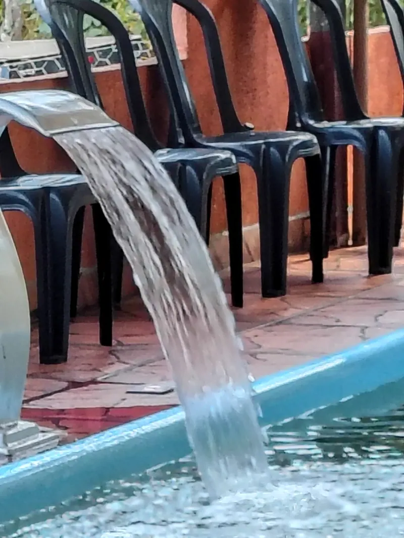 Queda d'água da piscina, com as cadeiras pretas enfileiradas atrás