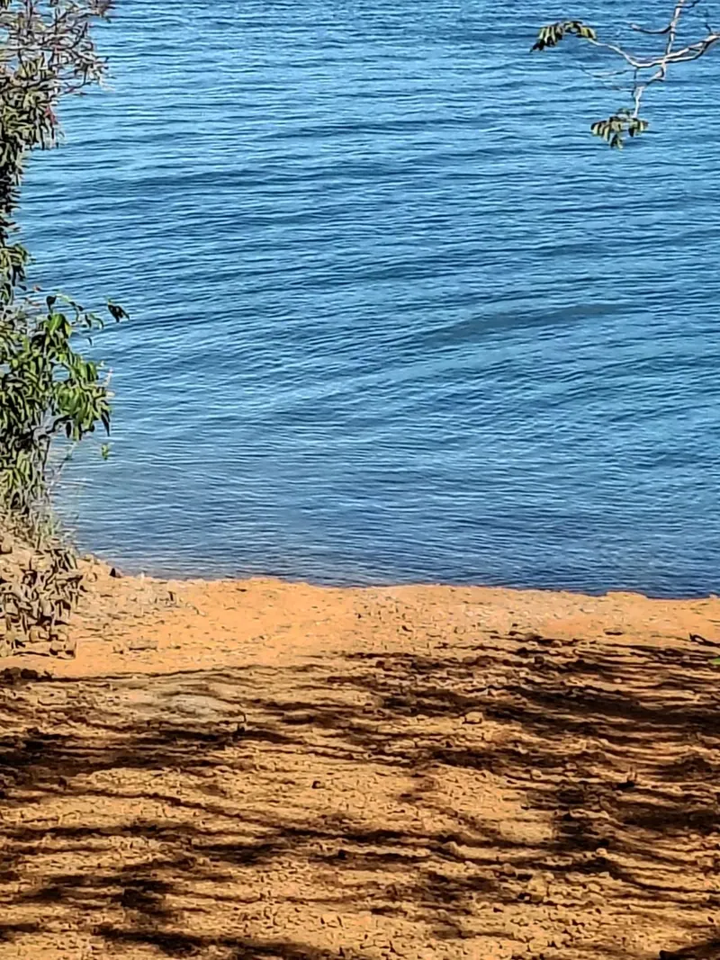 Margem de areia do lago Corumbá IV com a água azul