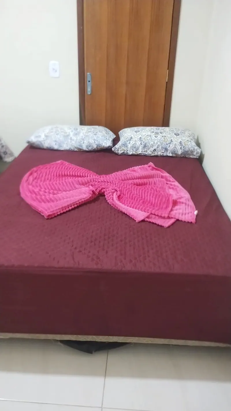 Suíte com cama de casal de colcha vinho e a porta de madeira ao fundo