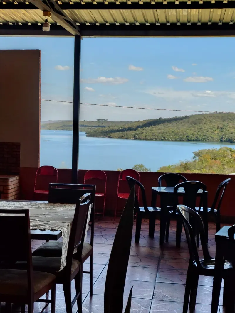 Área coberta com mesas e a vista do lago Corumbá IV ao fundo
